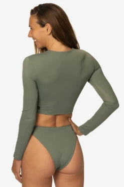 Taranaki Long Sleeved Crop Cut-Out Rashie - Eucalyptus 19 Taranaki Long Sleeved Crop Cut-Out Rashie - Eucalyptus -JOLYN Sales Swim Tops Taranaki Solid Eucalyptus Back Side TiaSurf MiskaSykora 021023